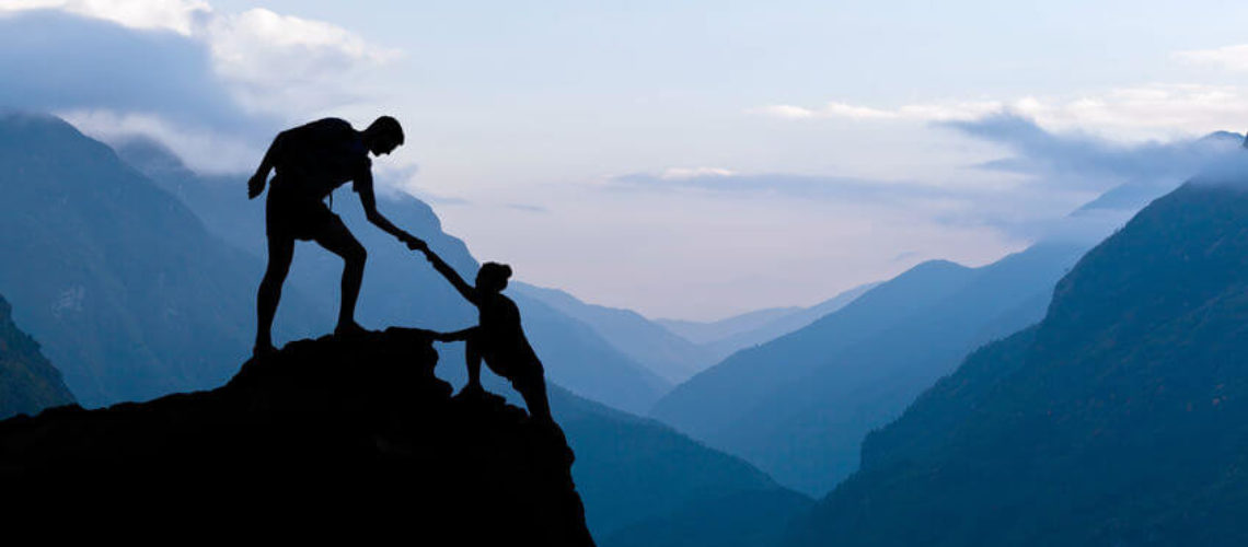 Teamwork couple helping hand trust assistance silhouette in mountains, sunset. Team of climbers man and woman hiker, help each other on top of mountain, climbing assistance, beautiful sunset landscape in Himalayas Nepal