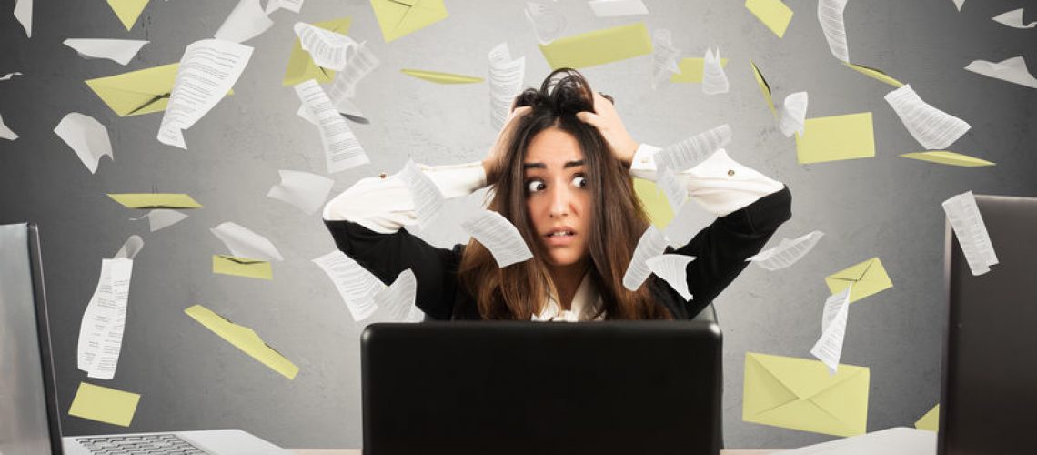 Businesswoman with a stunned expression and stressed front of three laptop